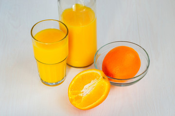 Orange juice in a glass bottle and glass on a white background