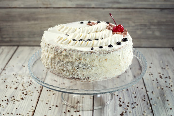 biscuit cake with cream and cherries on wooden background