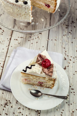 biscuit cake with cream and cherries on wooden background