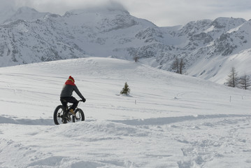 man use electric bicycle, e-bike, ebike, pedal on snow covered road, downhill mountain, specific...