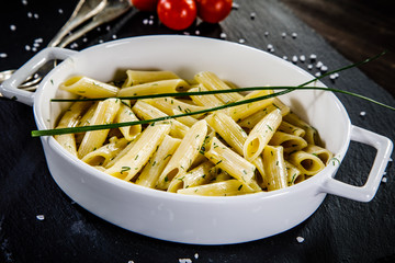 Penne with pesto and vegetables on wooden table