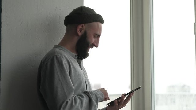 handsome beard man chatting with friends use digital tablet indoors, rejoices in correspondence