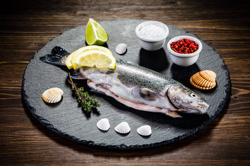 Fresh raw trout served on black stone on wooden table 