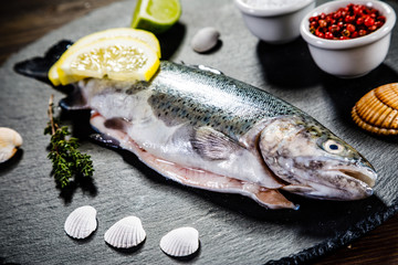 Fresh raw trout served on black stone on wooden table 