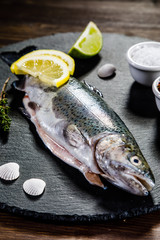 Fresh raw trout served on black stone on wooden table 