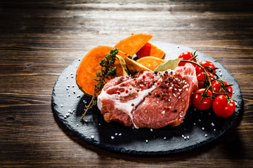 Fresh raw pork on black stone on wooden background 