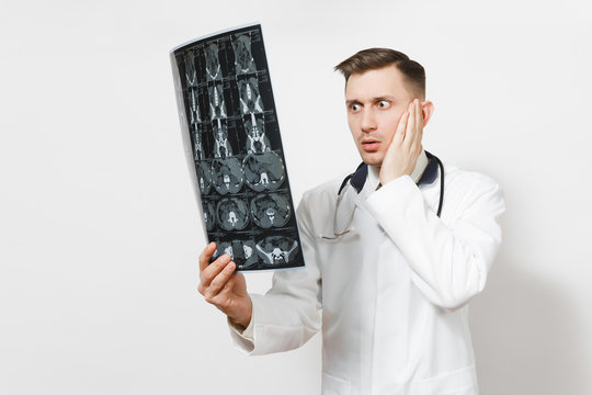 Shocked handsome young doctor man holds x-ray radiographic image ct scan mri isolated on white background. Male doctor in medical uniform, stethoscope. Healthcare personnel, health, medicine concept.