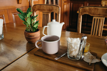 Cup of tea with honey and cinnamon on wooden background in cafe