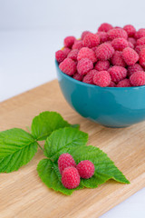 Home juicy raspberries poured in a bowl on a wooden table