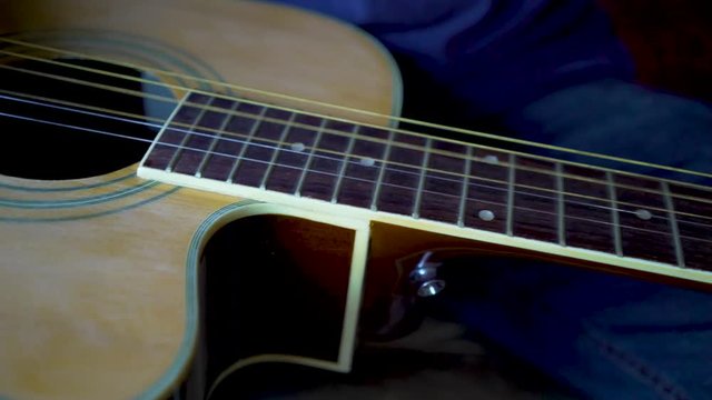 Very closeup on finger plucking the strings on the slide guitar.