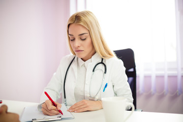 Female doctor writing down some information about her patient.