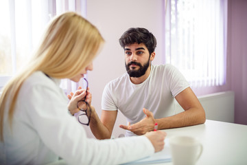 Handsome male patient talking with his doctor.