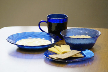 Breakfast includes oatmeal, coffee and cheese, and is served with blue glass utensils.
