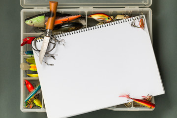 big notebook with fishing tackles on color paper background