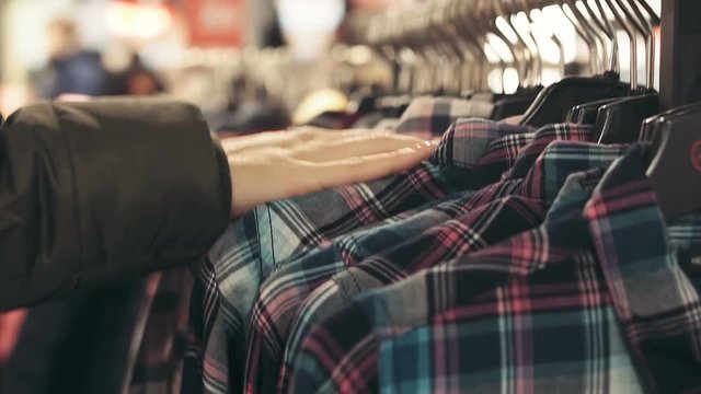 Women's hands choose a checkered shirt in the store