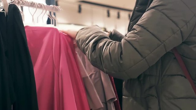 Women's hands chooses clothes in clothing store.