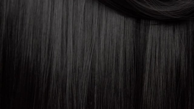 Hair texture background, no person. Black shiny hair curl falling down