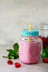 Mason jar mugs with fresh berry smoothies and fresh strawberries and raspberries on a gray stone or slate background. The concept of proper nutrition and health or detoxification.
