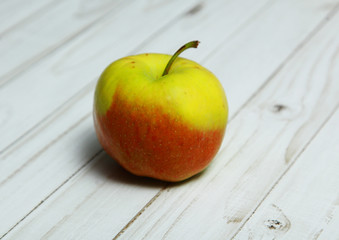 One Apple lies on a light wooden table
