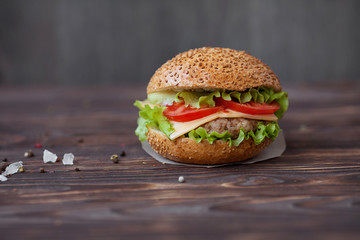 Closeup of home made beef burgers with lettuce and mayonnaise served on little wooden board. Dark background