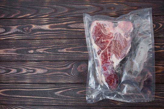 Vacuum Sealed Fresh Beef Meat On Wooden Background. Top View