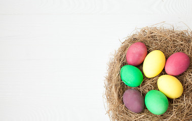 Easter eggs in the nest on white wooden background