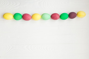Colorful Easter eggs on white wooden background.