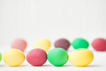 Colorful Easter eggs on white wooden background.