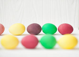 Colorful Easter eggs on white wooden background.