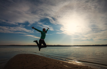 Woman jump on beach on sunrise sky background, freedom concept