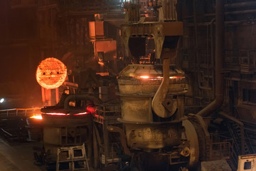 Melting of metal in a steel plant. High temperature in the melting furnace. Metallurgical industry. Factory for the manufacture of metal pipes. Bucket for feeding metal into molds.