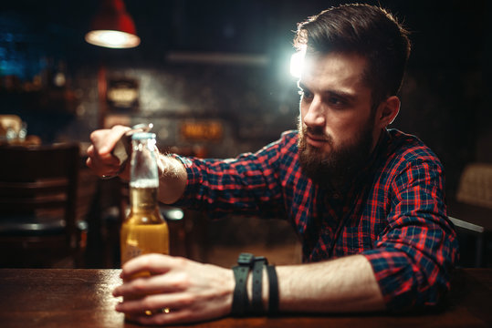Man sitting at the bar counter and opens bottle