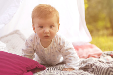 Fototapeta premium Little newborn infant baby boy kid on a plaid in park. Summer sunset. Copy space