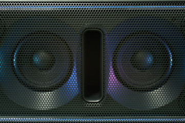 Loudspeaker grid with round openings and loudspeakers inside.