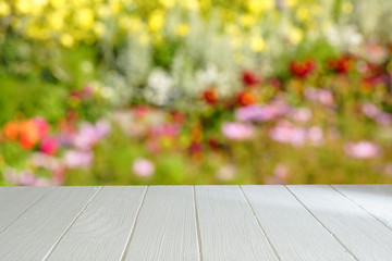 Empty table and blurred background of a blooming garden. White wooden table in a blooming garden. Blurred background.