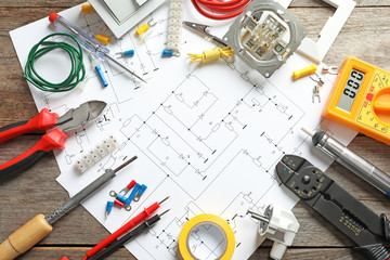 Different electrical tools and circuit diagram on wooden background