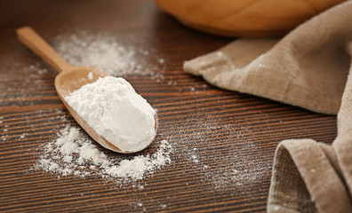 Scoop with wheat flour on wooden table