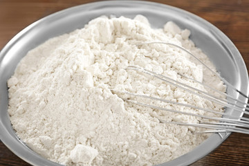 Whisk in bowl with wheat flour, closeup