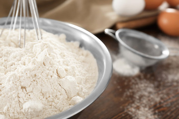 Whisk in bowl with wheat flour, closeup