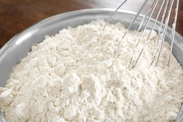 Whisk in bowl with wheat flour, closeup