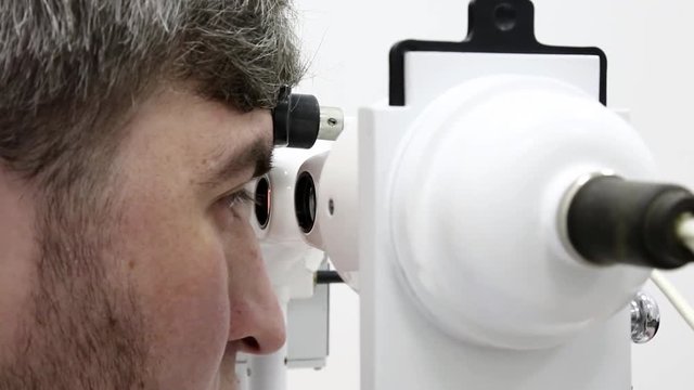 Patient in ophthalmology clinic. Man looks in synoptophore - ophthalmic instrument, used for diagnosing imbalance of eye muscles and treating them by orthoptic methods, for treatment of strabismus