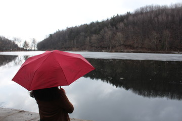 woman holding red umbrella near a lake