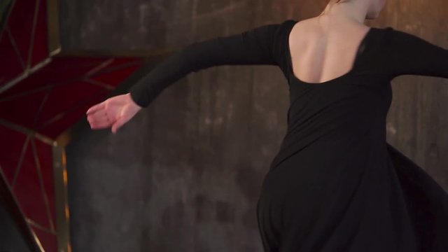 Adolescent girl is whirling in a dance. She is practicing her dancing motions, she is alone in class