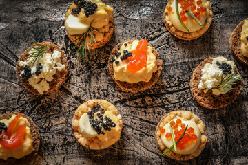 Obraz na płótnie Canvas Delicious canapes with black and red caviar on textured background