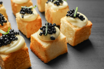 Delicious canapes with black caviar on  dark background