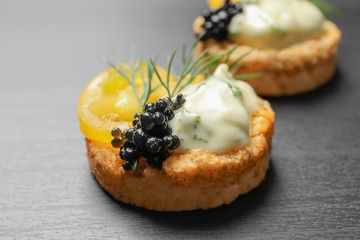 Delicious canape with black caviar on  dark background