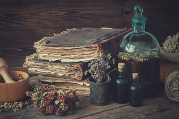 Tincture bottles, assortment of dry healthy herbs, old books, wooden mortar, sack of medicinal herbs. Herbal medicine. - obrazy, fototapety, plakaty