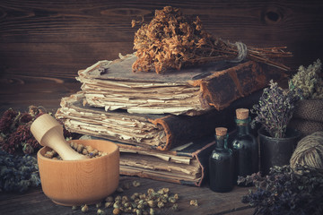 Tincture bottles, bunches of dry healthy herbs, stack of antique books, mortars, sack of medicinal herbs. Herbal medicine. - obrazy, fototapety, plakaty
