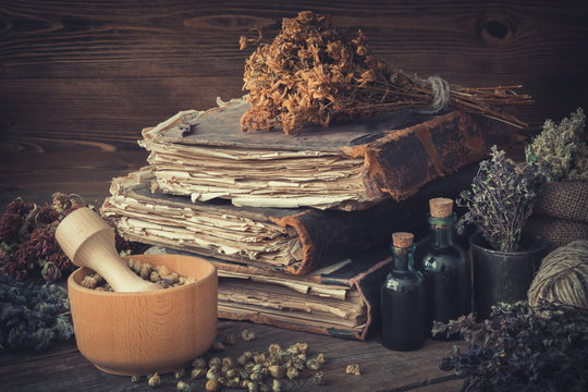 Tincture bottles, bunches of dry healthy herbs, stack of antique books, mortars, sack of medicinal herbs. Herbal medicine.