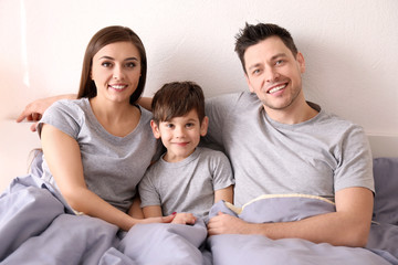 Happy parents with son in bed at home